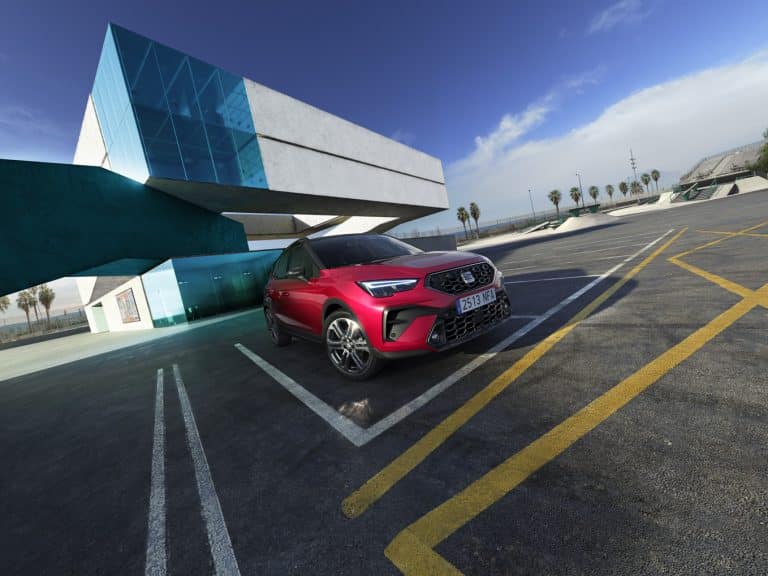 Czerwony SEAT Arona zaparkowany przy nowoczesnym budynku – miejski crossover idealny do firmy.