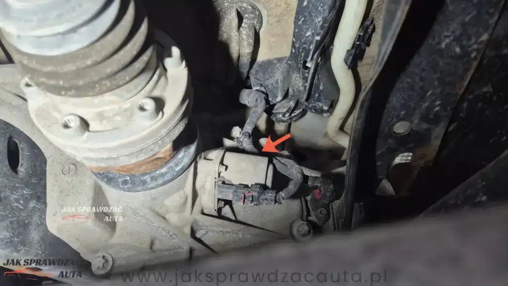 Nastawnik sprzęgła kłowego Quattro Ultra widoczny pod samochodem – szary cylindryczny silniczek z wtyczką elektryczną przy tylnym dyferencjale